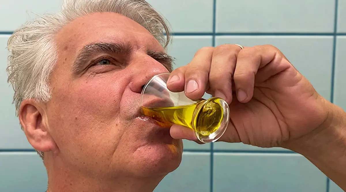 Homem bebendo óleo diretamente de um frasco de vidro