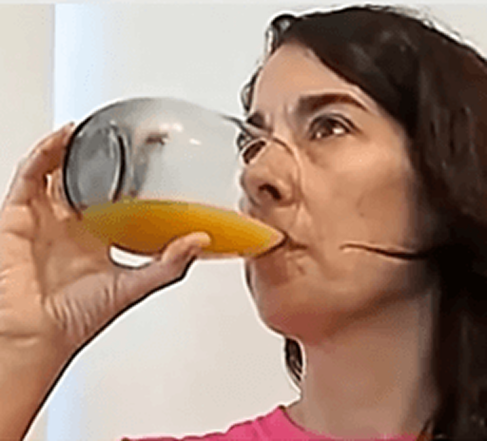 Mulher bebendo um copo de suco de laranja
