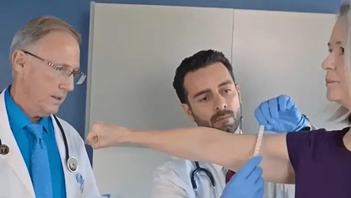 Equipe médica examinando o braço de uma paciente em consultório