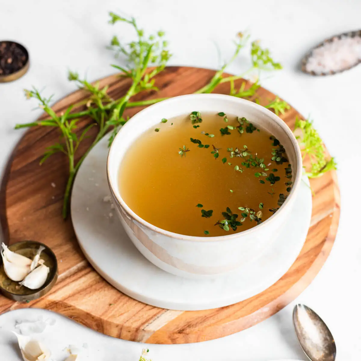 Tigela de caldo dourado com ervas frescas